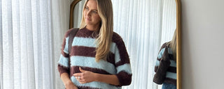 Woman in a striped top standing in a room in front of a mirror