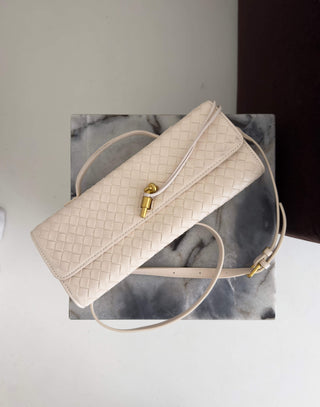 Cream woven handbag with gold clasp on a marble surface
