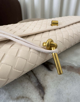 Cream handbag with gold clasp on a marble surface