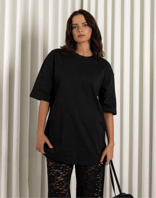 Woman wearing a black oversized t-shirt and black lace pants against a striped background Black longline cotton t-shirt with relaxed fit