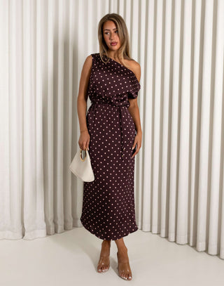 Woman wearing a polka dot dress against a white curtain background
Brown off shoulder midi dress with pale pink polka dots
