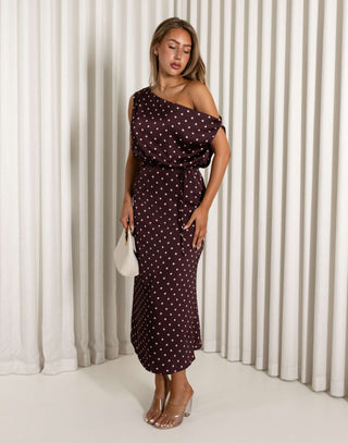 Woman wearing a polka dot dress against a white curtain background
Brown off shoulder midi dress with pale pink polka dots