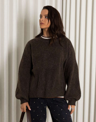 Woman wearing a brown oversized fluffy knit and black stud jeans with a white background