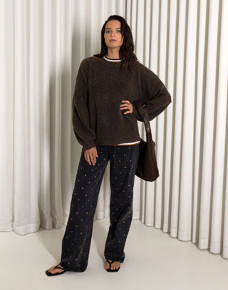 Woman wearing a brown oversized fluffy knit and black stud jeans with a white background