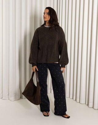 Woman wearing a brown oversized fluffy knit and black stud jeans with a white background