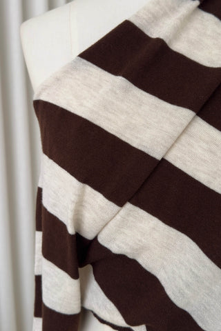 A close-up of a knit fabric draped over a white mannequin torso, showing wide alternating horizontal stripes in dark brown and warm off-white.