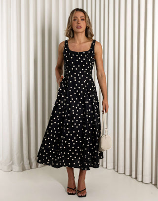 Woman wearing a black polka dot dress against a white curtain background Christine black A-line 100% cotton dress