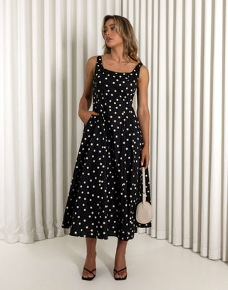 Woman wearing a black polka dot dress against a white curtain background Christine black A-line 100% cotton dress