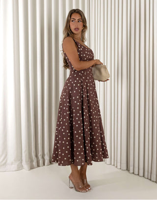 Woman wearing a brown polka dot dress against a white curtain background Christine A-line midi dress in polka dots with squoval neckline