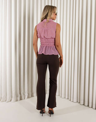 Woman wearing a pink sleeveless top and brown pants against a white curtain background Cole brown high-waist tailored flare pants with leg split