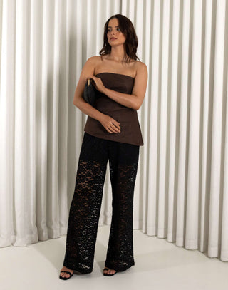 Woman wearing a strapless brown top and black lace pants against a white curtain background Black lace straight leg pants with high waist and sheer texture