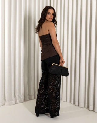 Woman wearing a strapless brown top and black lace pants against a white curtain background Black lace straight leg pants with high waist and sheer texture