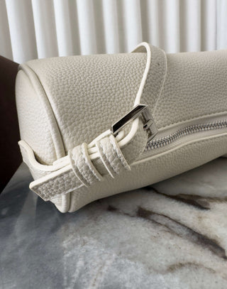 Beige leather clutch bag with a strap on a marble surface Danes ivory shoulder bag with adjustable strap