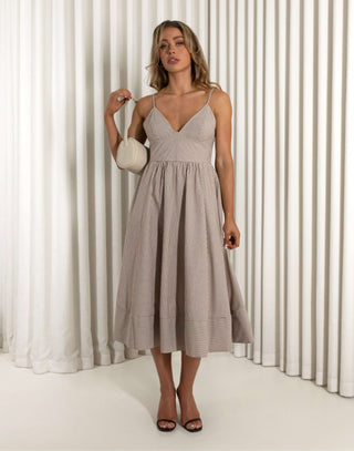 Woman wearing a light-colored dress standing against a white curtain background Emery brown fit and flare dress with flattering stripe placement