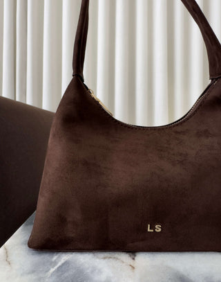 Brown suede handbag with 'LS' initials on a marble surface Erika brown faux suede shoulder bag