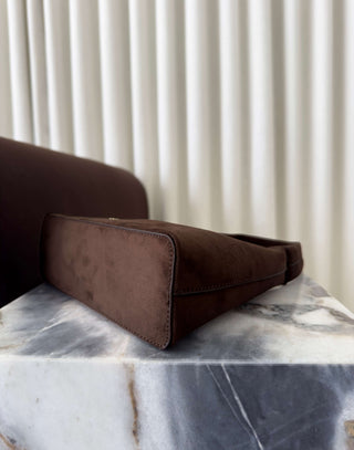 Brown leather wallet on a marble surface with a neutral background Erika brown faux suede shoulder bag