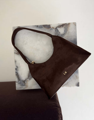 Brown handbag with gold clasp on a marble surface Erika brown faux suede shoulder bag