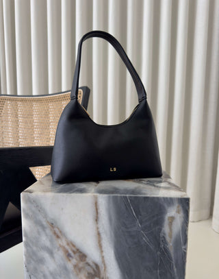 Black handbag on a marble block with a neutral background Erika black shoulder bag, compact, stand-flat base