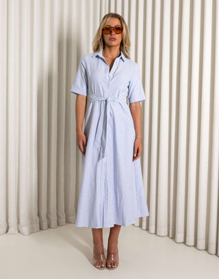 Woman wearing a blue and white striped dress with sunglasses against a neutral background Blue striped midi dress with collar and side pockets worn by model