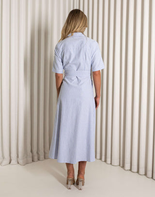 Woman wearing a blue and white striped dress with sunglasses against a neutral background Blue striped midi dress with collar and side pockets worn by model
