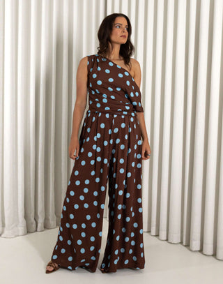 Woman wearing a brown top and matching pants with blue polka dots against a white curtain background Brown wide leg polka dot pants with relaxed fit