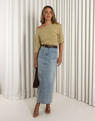 Woman wearing a yellow striped shirt and denim skirt against a white curtain background Jonathan denim maxi skirt with front patch pockets and full stretch