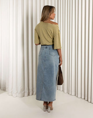 Woman wearing a striped shirt and denim skirt standing against a white curtain. Martin stripe versatile off shoulder long length top