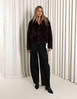 Woman wearing a brown and black outfit in front of white curtains