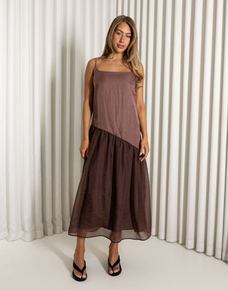 Woman wearing a brown dress standing against a white curtain background Nancy brown relaxed midi dress with adjustable straps
