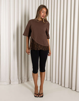 Woman wearing a brown top with lace detail against a neutral background Brown cotton t-shirt with lace hem detail
