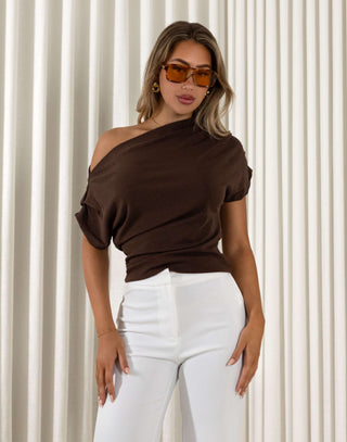 Woman wearing a brown one-shoulder top and white pants against a neutral background Nicole off shoulder gathered top in brown, fitted stretch