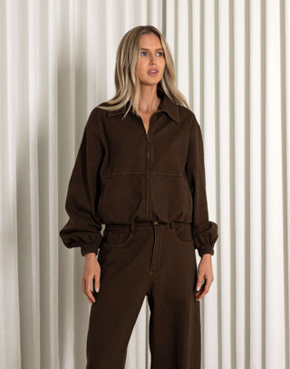 Woman wearing a brown jacket against a neutral background