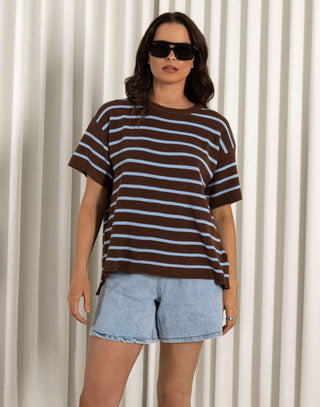 Woman wearing a striped shirt and denim shorts standing against a white curtain. Patrice striped cotton t-shirt with relaxed fit and short sleeves