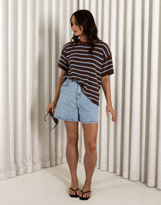 Woman wearing a striped shirt and denim shorts standing against a white curtain. Patrice striped cotton t-shirt with relaxed fit and short sleeves