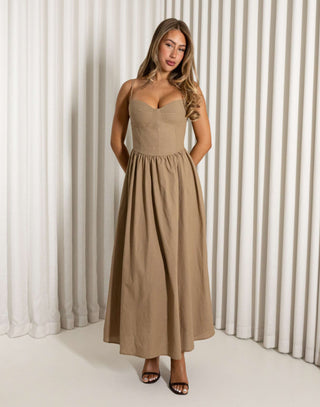 Woman wearing a beige dress standing against a white curtain background Robin mocha fit-and-flare maxi dress with wireless cups
