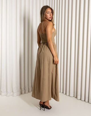 Woman wearing a brown dress standing against a white curtain. Robin mocha fit-and-flare maxi dress with wireless cups
