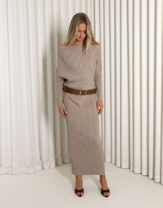 Woman wearing a brown ribbed top and skirt set against a white curtain background