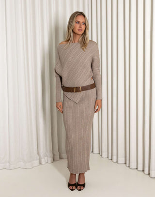Woman wearing a brown ribbed top and skirt set against a white curtain background