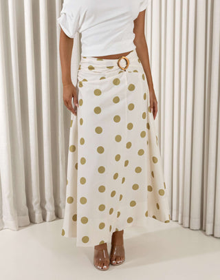 Person wearing a white top and polka dot skirt with a belt, standing against a neutral background. Vanessa cream polka dot maxi skirt with gold waist detail